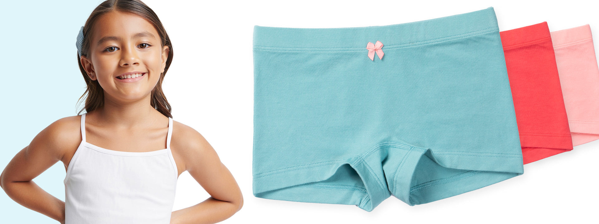 Young girl standing next to a set of light blue and pink sophie girls shortie underwear