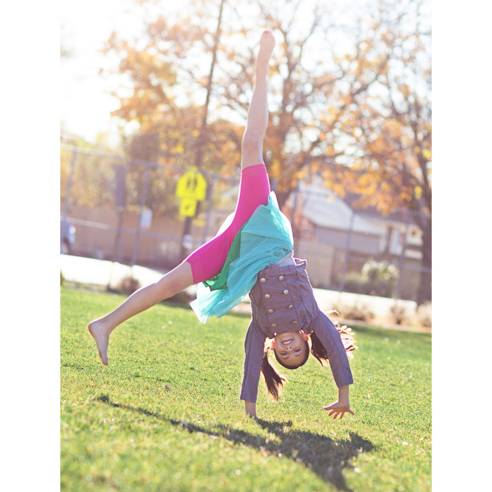 Girl doing cartwheel and wearing pink bike shorts under skirt
