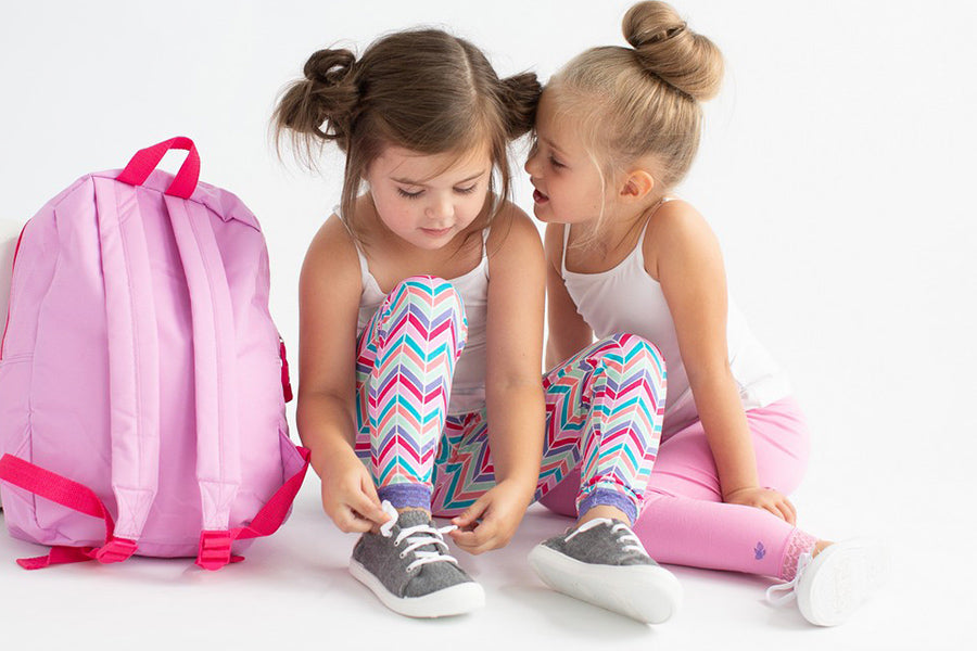 two girls in leggings and camisoles with pink backpack