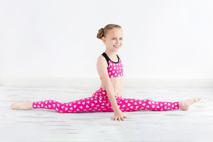 girl in pink leggings and racer back top doing split