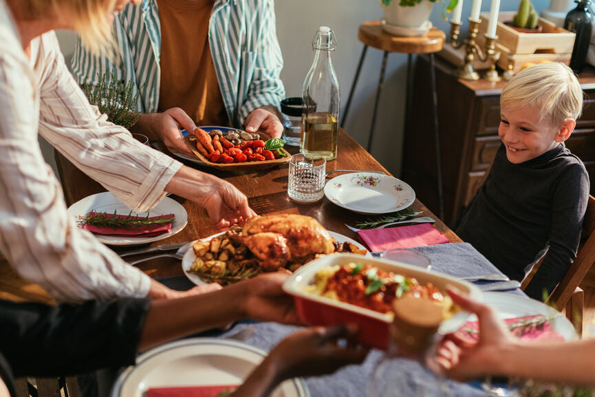 Group of friends celebrating Thanksgiving Day together, enjoying in delicious dinner. Little boy looking at food, smiling