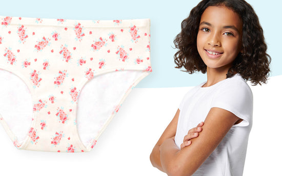 Young tween girl standing next to a floral-patterned organic underwear on a light blue background