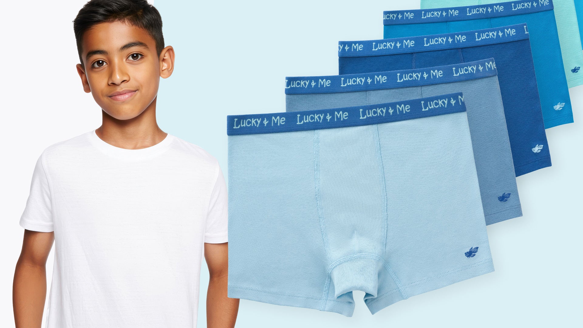 Boy standing next to Lucky & Me Grayson organic cotton underwear on a light blue background
