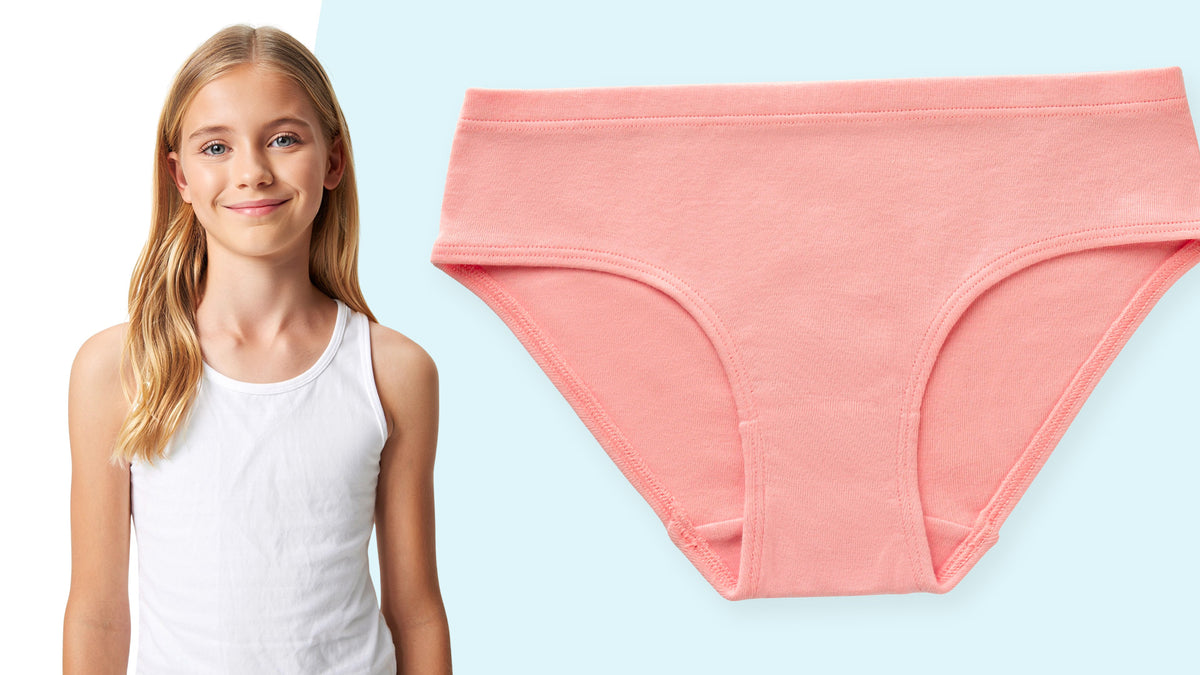 A young girl with blonde hair wearing a white tank top stands next to a flat-lay view of a coral pink organic cotton Ryleigh Tween Bikini.